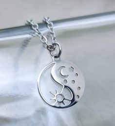 Sun moon dainty necklace. Yin yang symbol with sun moon and stars. Small, delicate pendant with mirror polished finish. Casual everyday wear. Gift for women girls birthdays. Pendant 15mm across. With 2mm flat cable chain. Available in various lengths to suit all tastes. Premium  stainless steel -  * Durable * Waterproof * Hypoallergenic * Tarnish and scratch resistant * High strength * Lasting colour * Shiny  * Comfortable to wear * Affordable  We keep packaging to a minimum. Our products come g Trendy Silver Round Charm Necklaces, Trendy Moon Charm Jewelry As Gift, Trendy Moon Charm Jewelry Gift, Trendy Round Jewelry With Moon Charm, Trendy Silver Jewelry With Moon Charm, Trendy Silver Necklace With Moon Charm, Dainty Sun And Moon Charm Necklaces As A Gift, Dainty Sun And Moon Design Charm Necklace As Gift, Dainty Sun And Moon Charm Necklace Gift