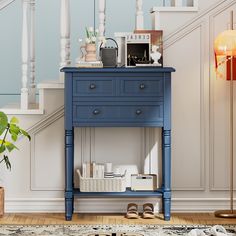 a blue table sitting under a stair case next to a lamp and potted plant