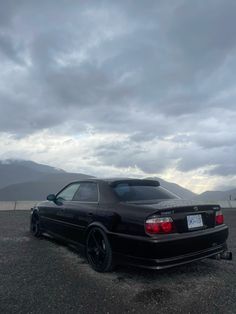 a black car parked on top of a gravel field