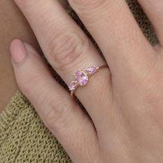 a woman's hand with a pink diamond ring on her left and two diamonds on the right