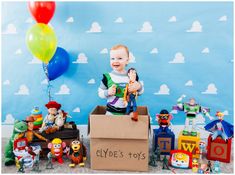 a little boy sitting in a box with toy characters around him