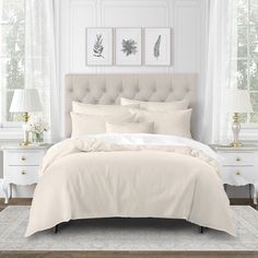 a bed with white linens and pillows in a bedroom next to two pictures on the wall