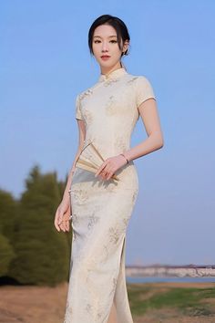 A beautiful woman in a long white qipao Chinese dress with short sleeves Elegant Beige High Neck Dress, Elegant High Neck Beige Dress, Elegant Formal Ao Dai Maxi Length, Elegant Formal Maxi Length Ao Dai, Elegant Maxi Length Ao Dai For Formal Occasions, Formal Stand Collar Ao Dai, Elegant Spring Cheongsam With Stand Collar, Spring Elegant Cheongsam With Stand Collar, Elegant Fitted Midi Dress With Stand Collar