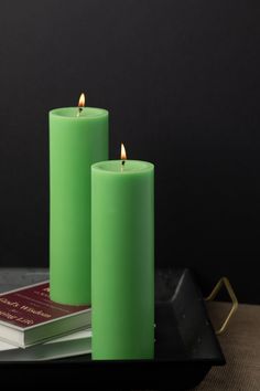 two green candles sitting on top of a tray