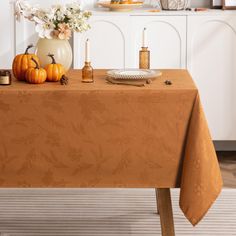 an orange table cloth with pumpkins and candles on it