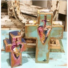 three wooden crosses with hearts painted on them and one has a cross in the middle