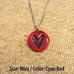 a necklace with a red heart in the center on a woven cloth tablecloth background