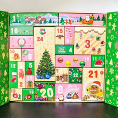 an open christmas calendar on a table with santa's tree and other holiday decorations