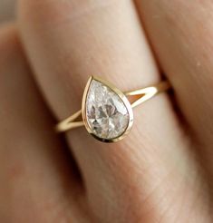 a woman's hand with a yellow gold ring and a white diamond on it