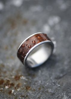 a close up of a silver ring with wood in the middle and writing on it