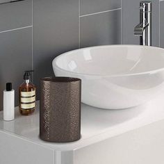 a white sink sitting on top of a counter next to a bottle and soap dispenser