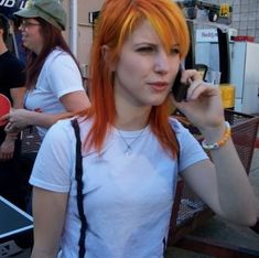 a woman with orange hair talking on her cell phone