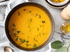 an overhead view of a bowl of soup on a marble table with garlic and herbs