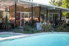 a house with a pool in front of it and lots of plants on the side