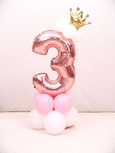 the number three balloon with a crown on top is shown in pink and white balloons