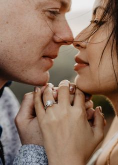 a man and woman kissing each other while holding their hands close to one another's face