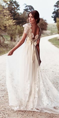 a woman in a white dress is walking down the road with her hand on her hip