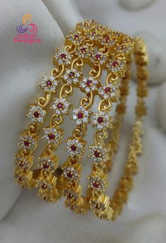 Material: High-quality gold plating on durable alloy Stones: Ruby and clear stones arranged in a floral pattern Design: Intricate floral design with a modern twist Set: 4 bangles  Size: Available in 2.4, 2.6, 2.8 and 2.10 sizes for a perfect fit Finish: Lustrous gold plating for a radiant look Key Features: Premium Quality: Made with superior materials to ensure long-lasting shine and durability. Elegant Design: The combination of gold and multi-color stones creates a timeless and versatile piec Gold Ruby Bangle For Celebration, Festive Gold Bangle With Ruby, Festive Gold Ruby Bangle, Ruby Bangle With Intricate Design, Luxury Gold Ruby Bangle, Ruby Bangles, Gold Jewellry, American Diamond Necklaces, Gold Plated Bangles