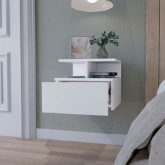 a small white shelf on the wall next to a bed