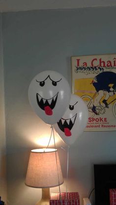 two balloons with faces on them sitting next to a lamp