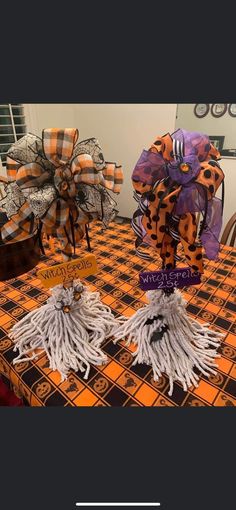 two halloween decorations on top of a table with orange and black gingham cloth