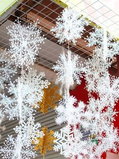 snowflakes hanging from the ceiling in front of a building with red and yellow walls