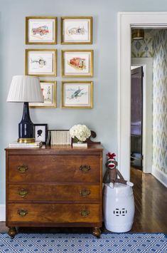 a room with pictures on the wall and a chest of drawers in front of it