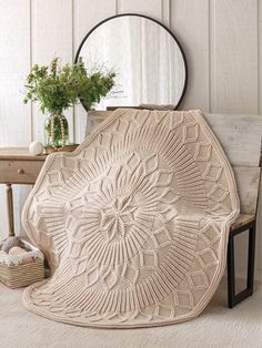 a crocheted blanket sitting on top of a wooden bench next to a mirror