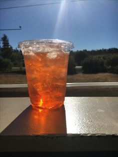 a plastic cup filled with liquid sitting on top of a table next to a window