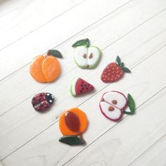 several fruit shaped magnets sitting on top of a white table