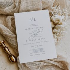 the wedding stationery is laid out on top of some fabric with flowers in the background