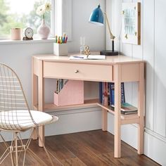 a desk with a chair, lamp and bookshelf in front of a window