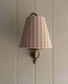 a pink and white striped lamp on a wall