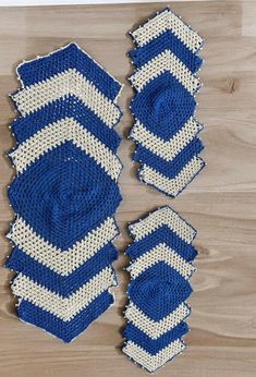 two blue and white crocheted coasters sitting on top of a wooden table