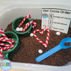 a container filled with dirt and candy canes next to a hot cocoa order sign