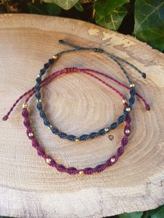 two bracelets with beads on top of a piece of wood next to green leaves