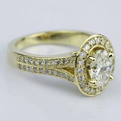 a yellow gold engagement ring with an oval cut diamond surrounded by pave set diamonds