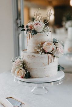 a three tiered cake with flowers on top and the letter g on it's side