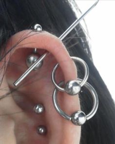 a woman with three piercings on her ear and two balls attached to the side of her ear