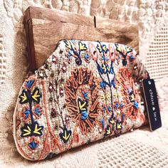 Add A Touch Of Bohemian Chic To Your Outfit With This Chloe & Lex Clutch Bag. The Cream/Multicolored Woven Tapestry Exterior Is Adorned With Beaded Accents For Added Texture. The Wooden Handle/Strap In Brown Complements The Bronze Hardware Inside, Creating A Cohesive Look. This Medium-Sized Clutch Is Perfect For Any Occasion, Whether It's For Travel, Casual Outings, Formal Events, Or Workwear. The Bag Features A Hinged Closure, Interior Lining Is Made Of Beige Polyester, And The Bag Measures App Bohemian Woven Party Bag, Spring Bohemian Beaded Bags, Woven Tapestry, Bronze Hardware, Jelly Shoes, Tapestry Weaving, The Cream, Key Card Holder, Bohemian Chic