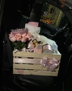 a wooden crate filled with pink roses in the back seat of a car at night