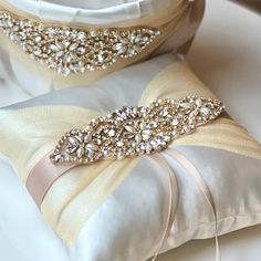 two white pillows with beading on them sitting next to each other in front of a pillow