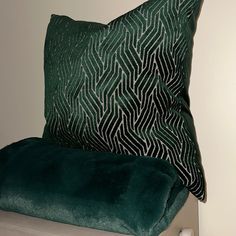 a green pillow sitting on top of a white table next to a black and white pillow