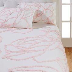 a bed with pink and white pillows on top of it