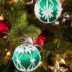 two green and white ornaments hanging from a christmas tree