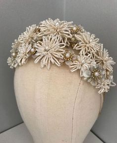 a white headpiece with flowers and pearls on top of a mannequin's head