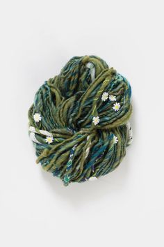 a skein of green and blue yarn with white flowers on it's end