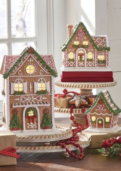 three gingerbread houses are decorated with christmas decorations and candy canes on the table