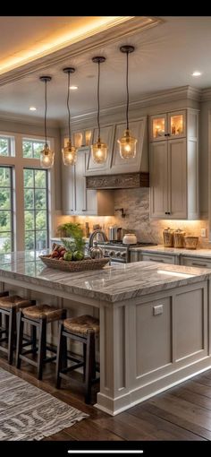 a large kitchen with lots of counter space and lights hanging from the ceiling over the island