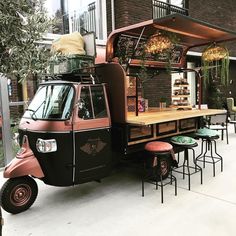 the food truck is parked on the side of the street with tables and stools